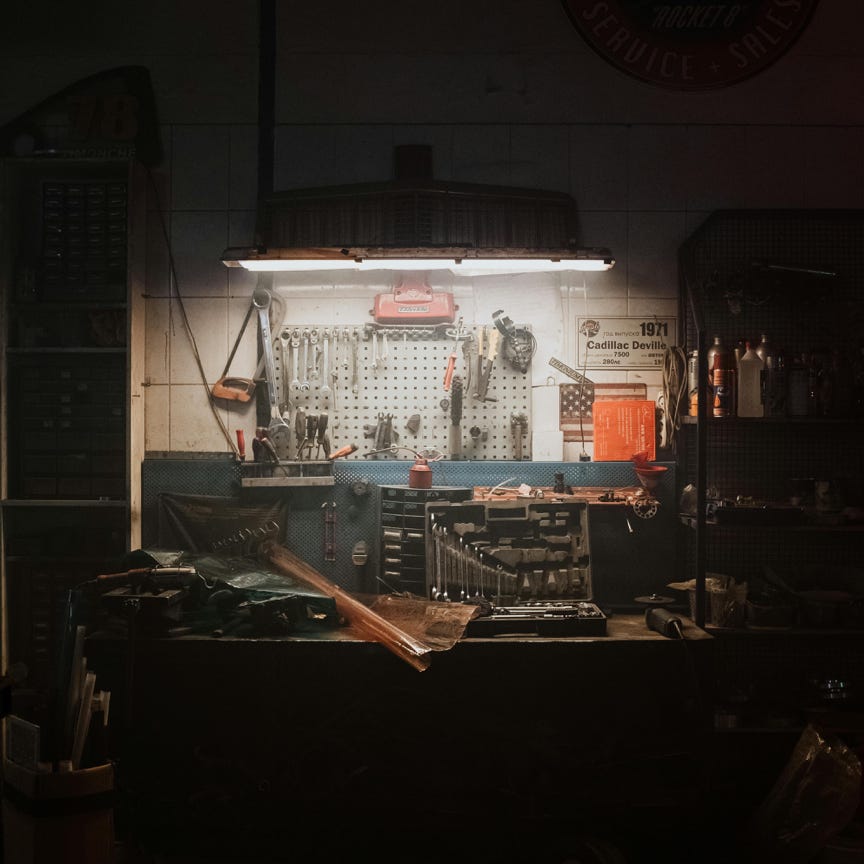 A moody, dimly lit workshop with neatly arranged tools and equipment, evoking a sense of craft and diligence.